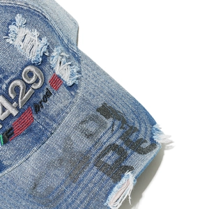 Macro shot of distressed blue denim baseball cap with 4.29 embroidery and graffiti details