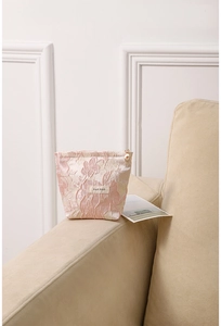 Close-up of pink embossed floral jacquard makeup bag with a zipper and brand label