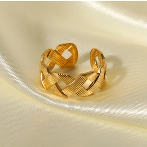 Detailed view of golden twisted stainless steel ring with elegant brushed texture on silk