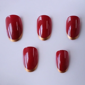 Faux ongles ovales bordeaux classiques avec pointes françaises dorées et fini brillant