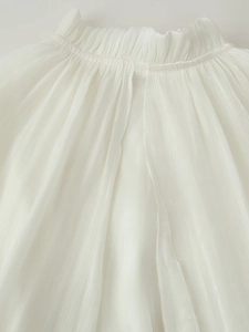 Detailed close-up of white chiffon dress featuring delicate pleated texture and ruffles