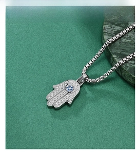 Macro shot of silver Hamsa Hand pendant with zircon micro-paving and blue gem center