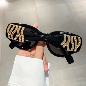 Retro black sunglasses with gold wave diamond-encrusted temples and dark lenses