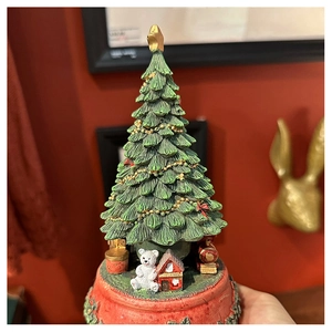Close-up of a Christmas tree music box with festive bears and train on a red base