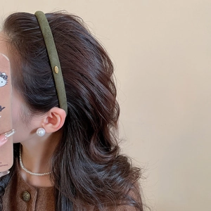 Gros plan du serre-tête floqué vert olive avec logo doré et détails de perles élégants