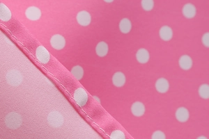 Detailed close-up of pink polka dot fabric showing precision stitching and fine texture
