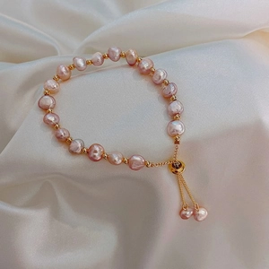 Detailed close-up of Baroque pearl bracelet with gold beads on beige silk background