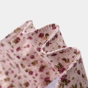 Vue détaillée du tissu floral rose avec des roses rouges et des coutures de bord ondulées