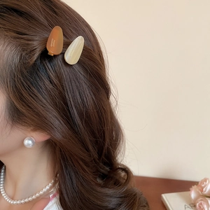 Vue détaillée de barrettes en acrylique ambre et beige portées avec élégance