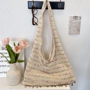 Close-up of bohemian knit tote bag featuring shell tassels and colorful yarn accents