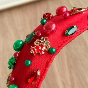 Close-up of Christmas headband featuring red fabric, rhinestones, pearls and festive bells