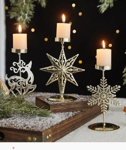 Close-up of golden metal reindeer and snowflake candle holders on a snowy wooden tray