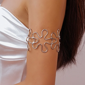 Detail of silver wavy floral arm cuff on model arm over white satin fabric