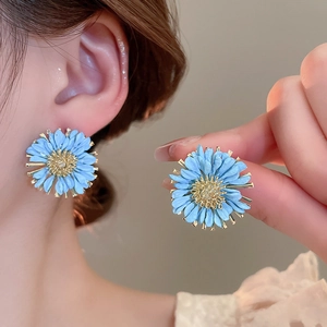 Detail of light blue daisy stud earrings with golden center on model and in hand
