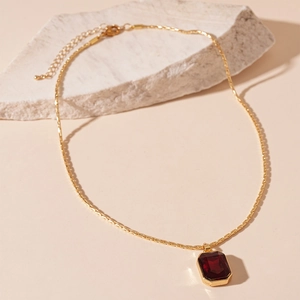 Detailed view of vintage gold necklace with rectangular deep red gemstone pendant