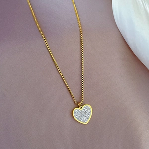 Close-up of a gold-plated heart pendant with micro-pave zircons on a delicate box chain