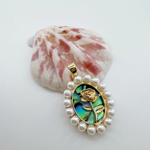 Detailed close-up of 18K gold rose pendant with abalone shell and pearl accents