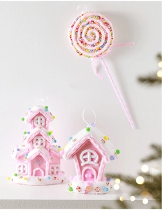 Close-up of pink gingerbread house and lollipop Christmas ornaments with velvet texture