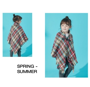 Detail of red and green plaid kids poncho featuring fringe and toggle horn buttons