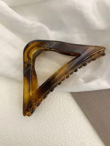 Macro shot of triangular tortoise shell hair claw with amber texture on linen