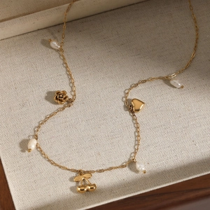 Collier doré avec breloques rose, cœur et cerise dans un coffret à bijoux en bois