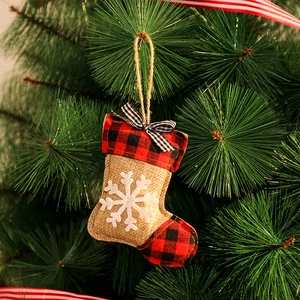 Détail de chaussette de Noël en toile avec motif à carreaux et flocon sur sapin décoré