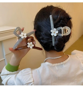 Detail of large floral claw clip featuring white resin flowers on a translucent grey base