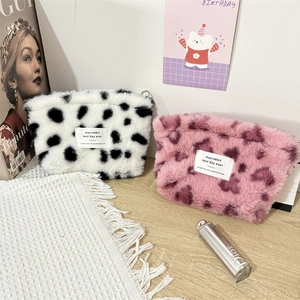 Close-up of plush storage bag with cow print and heart leopard patterns on textured fabric
