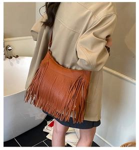 Caramel brown fringe shoulder bag in synthetic leather shown on a model side view