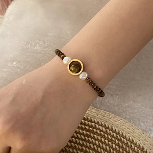 Detail of beaded tiger eye bracelet with pearls and gold ring on a woman wrist