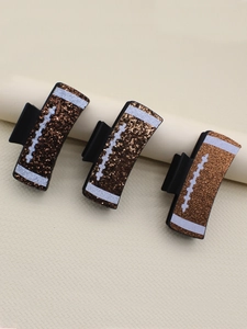 Detailed view of three brown glitter football hair clips with white stitching accents
