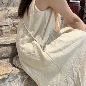 Crossbody pearl and silver chain accessory with heart pendant worn by a model