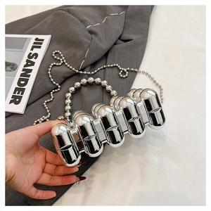 Detail of silver acrylic capsule clutch bag with metallic bead handle and crossbody chain