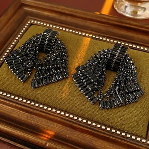 Close-up of black rhinestone bow earrings on green velvet with vintage lighting