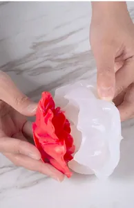 Primer plano de un molde de silicona para flores al desmoldar un jabón de peonía roja