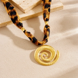 Fashion leopard print ribbon chain necklace with golden spiral charm on a beige background