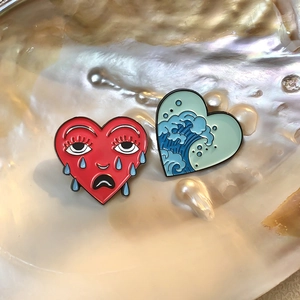 Creative cartoon heart enamel pins with crying face and wave design in a seashell