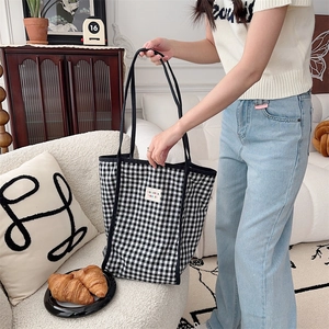 Detail of a large checkerboard knit tote bag in a cozy home setting with warm lighting