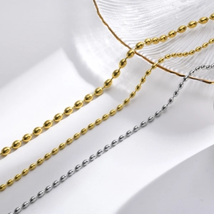 Three minimalist titanium steel bead necklaces in gold and silver finishes on a glass plate