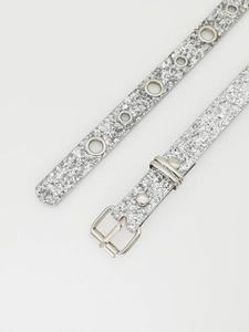Detail of silver glitter Y2K belt featuring metallic buckle and adjustable metal eyelets