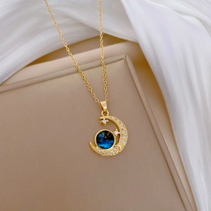 Gold star and moon necklace with blue starry gem and crystals on silk background