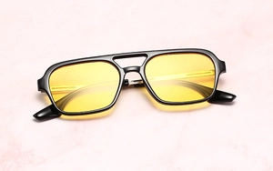 Detail of vintage pilot sunglasses with black frame and yellow lenses on marble background