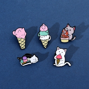 Flat lay of colorful enamel cat pins with ice cream designs on a blue background