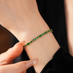 Close-up of gold-plated bracelet featuring alternating green zircons and square gems