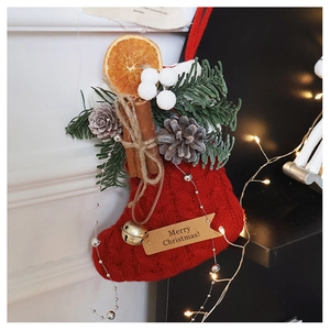 Close-up of red knit Christmas stocking with cinnamon, dried orange and pine cones