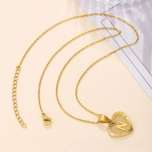 Close-up of gold heart pendant necklace with letter N engraving and lobster clasp