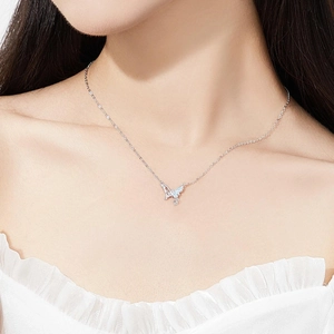 Silver butterfly necklace with light blue gradient pendant worn by a female model