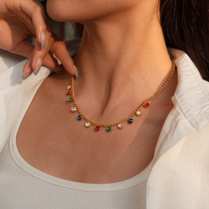 Detail shot of a gold necklace with multicolored crystal charms on a female model