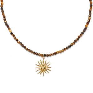 Macro shot of faceted brown stone beads with a golden sun face pendant necklace