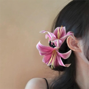 Close-up of a realistic pink lily flower hair claw clip worn on a model hair